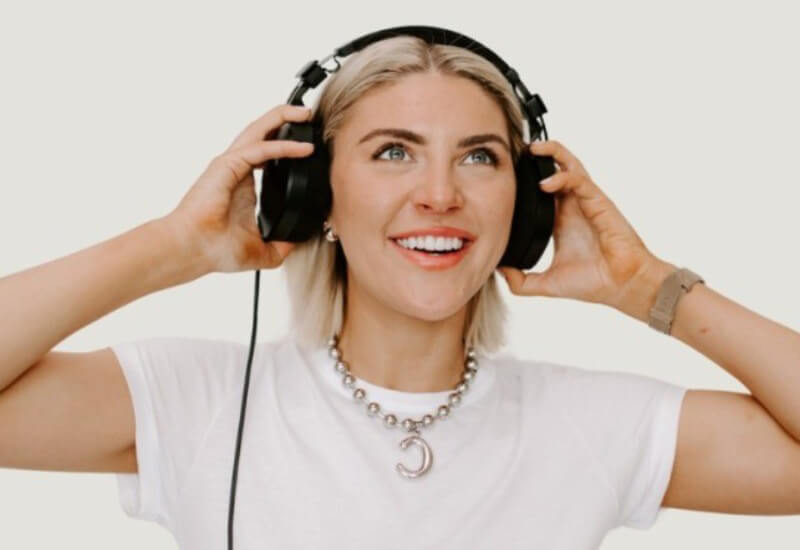 The Content Factory A person with short blonde hair wearing a white t-shirt and headphones smiles and looks slightly upward. In Austin, Texas